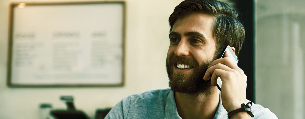 Photo of a man smiling while talking on a mobile phone